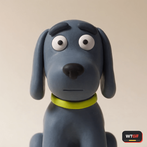 A slate blue clay dog with floppy matching ears tilts its head one way, then slowly the other, holding a flat unblinking stare at the camera like it is waiting for you to hear yourself.